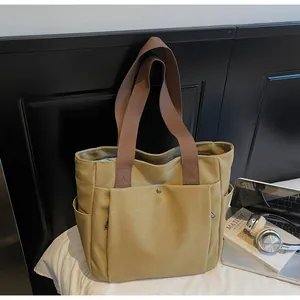 Close-up of mustard canvas tote bag with side pockets and brown wide shoulder straps