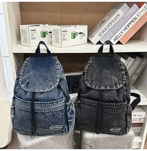 Detail of vintage denim backpacks in blue and black with drawstring and flap closure
