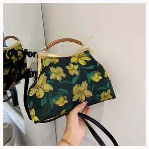 Detail of floral embroidery on green fabric bag with elegant wooden handle and metal frame