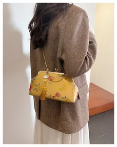 Detail of yellow silk embroidery bag with golden floral patterns and elegant tassel
