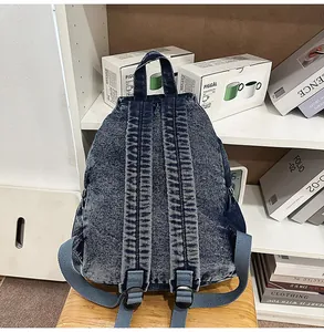 Detailed view of adjustable straps on a vintage washed denim backpack with metal hardware