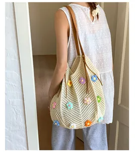 Close-up of crochet knit tote bag with colorful 3D floral accents and leather straps