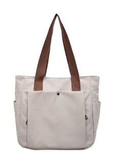 Minimalist canvas tote bag in off-white with brown straps and functional side pockets