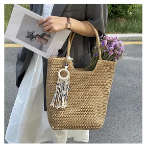 Détail du sac en paille tressée ajourée avec pendentif pompon et perles mauvais œil