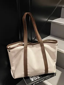 Minimalist canvas tote bag with brown leather straps and silver rivets for casual use