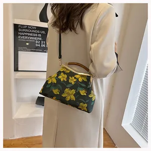 Detail view of floral fabric handbag featuring retro wooden handle and gold metal frame