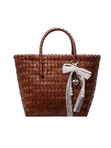 Brown woven straw tote bag with white lace bow and pearl charm for beach vacation