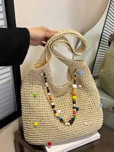 Handmade woven straw beach bag with colorful pompoms and bohemian beaded strap detail