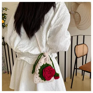Detalle de bolso tejido a mano con cordón, rosa roja grande y correa de hombro