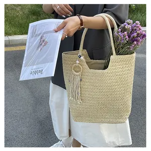 Détail du grand sac cabas tissé beige avec anneau en bois décoratif et longues franges