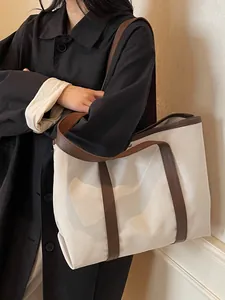 Minimalist canvas tote bag with brown leather trim and wide shoulder strap for women