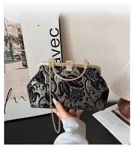 Detail of dark velvet floral handbag with gold metal frame and elegant chain strap