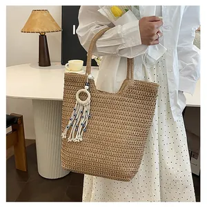 Détail du sac cabas en paille tressée avec pompon œil bleu et texture faite main