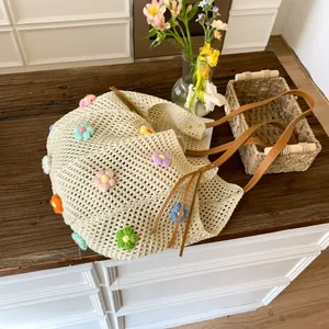 Detailed close-up of beige crochet tote bag featuring 3D floral accents and brown leather handles