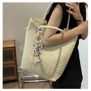 Détail du grand sac cabas tissé beige avec charme à franges et œil protecteur