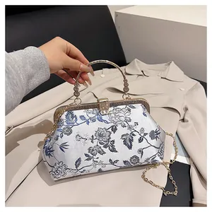 Close-up of Chinese style embroidery and golden circular handle on a white silk handbag