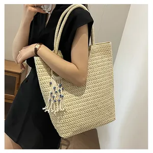 Détail du sac cabas en paille tressée avec pompon bohème et perles oeil d'orient