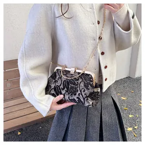 Detail of vintage floral jacquard kiss-lock bag with a delicate gold chain strap