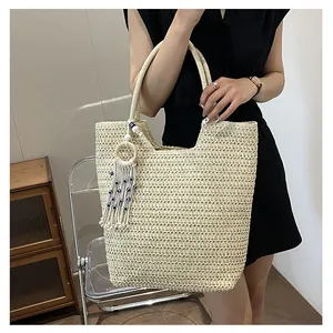 Détail du cabas tissé beige avec charme à pompon et perles bleues contre le mauvais oeil