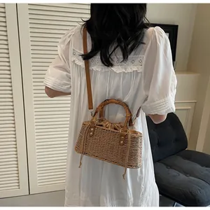 Detalle de bolso de paja con asa de bambú y correa de hombro de cuero marrón casual