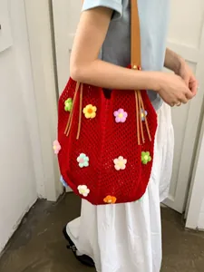 Red crochet knit tote bag with 3D colorful flowers and leather straps worn by model