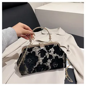 Detail of vintage jacquard handbag with black floral embroidery and gold metal handle