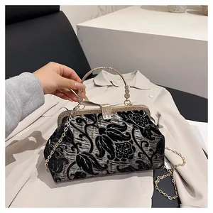 Detailed macro view of vintage black velvet clutch with golden floral embroidery and metal frame