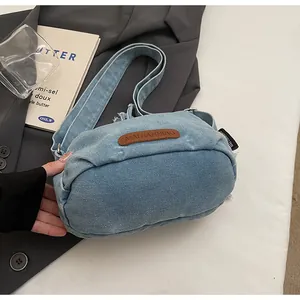 Dettaglio della borsa in denim blu con patch logo in pelle marrone e trama morbida