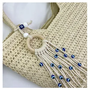 Gros plan d'un sac cabas en paille tressée avec anneau en bois et breloque œil bleu