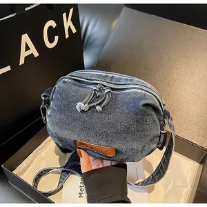 Dettaglio borsa a tracolla in denim blu con logo in pelle marrone ed etichetta tessuta