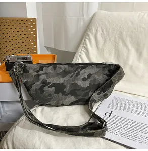 Detail of canvas camo crossbody bag with black zipper and adjustable strap on white background