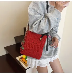 Detail der roten Häkeltasche mit 3D-Erdbeer-Anhängern und gestrickter Blumenstruktur