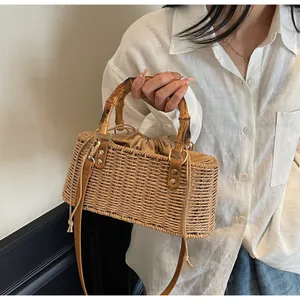 Detalle de bolso de paja con asa de bambú, forro con cordón y correa de hombro ajustable