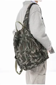 Side view of a large camouflage canvas backpack worn by a person on a white background
