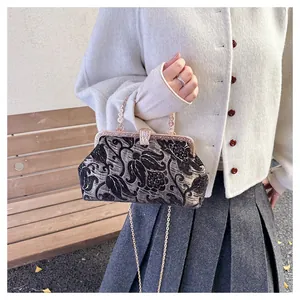 Detail of vintage floral jacquard shell bag with gold metallic frame and chain strap