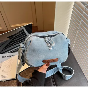 Dettaglio borsa in denim azzurro con etichetta in pelle e cerniera con nappe sfrangiate