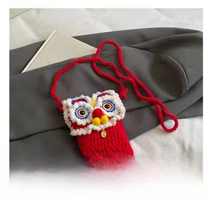 Détail de la pochette artisanale en tricot rouge avec motif lion de danse traditionnel