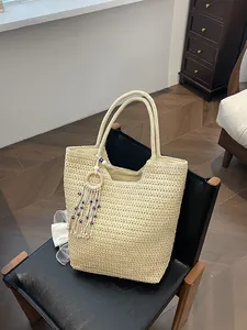 Sac cabas chic en paille tressée crème avec breloque œil bleu sur fauteuil en cuir