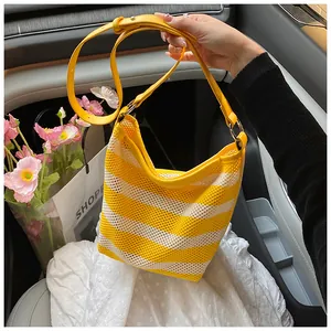 Close-up of woven mesh hobo bag with yellow stripes and adjustable leather strap