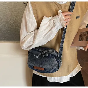 Dettaglio della borsa a mezzaluna in denim vintage con doppia cerniera indossata dal modello