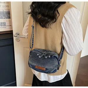 Dettaglio ravvicinato della borsa a tracolla in denim lavato vintage con logo in pelle