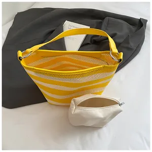 Close-up of yellow striped mesh tote bag with a canvas pouch on fabric background