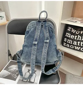 Detail of washed denim backpack on a black leather chair with textured blue fabric