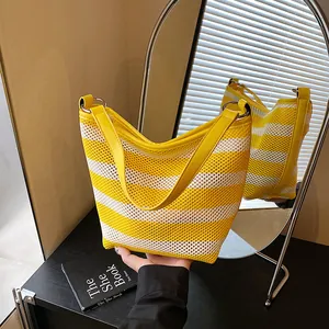 Detail of yellow and white striped mesh tote bag with PU leather strap and metal ring