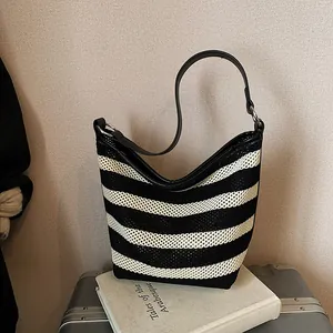 Detail of woven black and white striped tote with leather handle and silver ring buckle