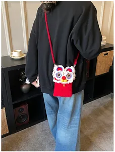 Détail d'un sac bandoulière rouge tricoté à la main avec motif lion et fourrure blanche