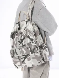 Large camouflage canvas backpack in grey and black pattern worn by model on white background