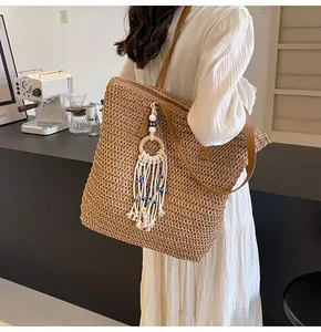 Detail of hand-woven straw tote bag with bohemian tassel and eye bead charm