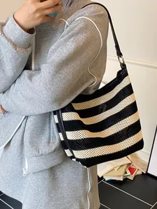 Striped woven shoulder bag with black leather strap and spacious interior for beach vacation