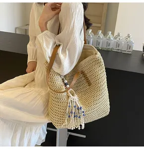 Close-up of straw woven tote bag with leather handles and ethnic tassel on a model